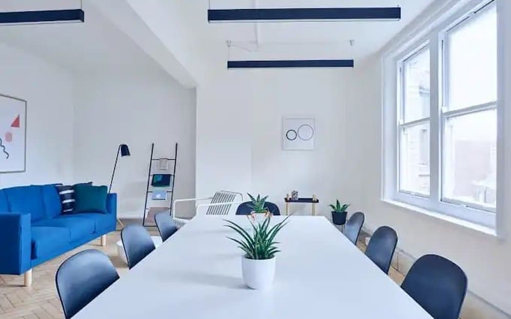 A bright, tidy office with a conference table, seating area and clean floors.